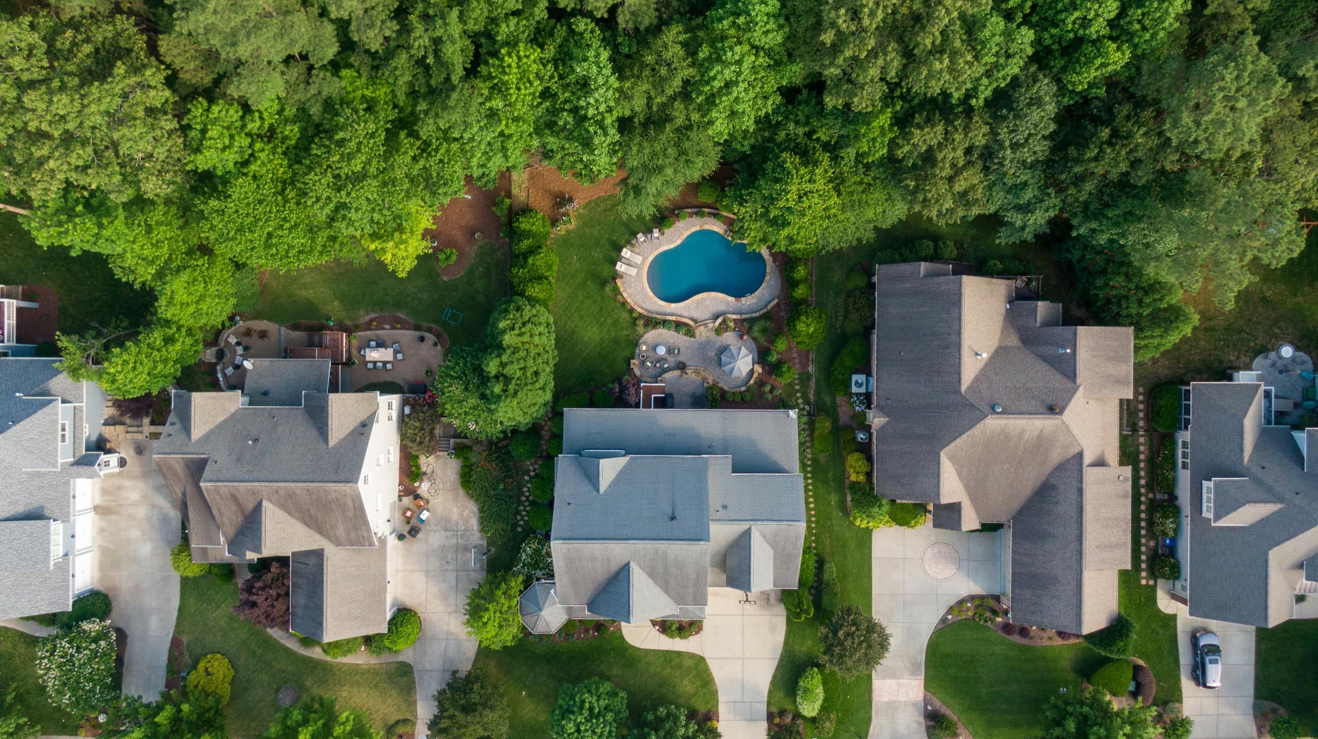 Aerial view of an upscale residential neighborhood with manicured lawns and pools